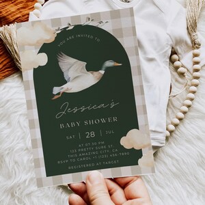 May include: A baby shower invitation with a green and white gingham pattern. The invitation features a watercolor illustration of a duck flying in front of a green circle. The text on the invitation reads "You are invited to Jessica's Baby Shower Sat 28 Jul at 07.30 PM 123 Pretty Sure St. This Amazing City, CA RSVP to Carol (123) 456-7890 Registered at Target"