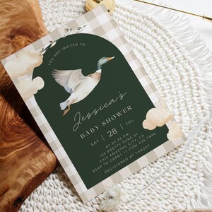 May include: A green and white gingham patterned baby shower invitation with a watercolor illustration of a duck flying. The text reads "You are invited to Jessica's Baby Shower Sat 28 Jul at 07.30 PM 123 Pretty Sure St. This Amazing City, CA RSVP to Carol +1 (123) 456-7890 Registered at Target"