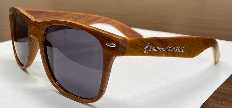 May include: Brown wood-framed sunglasses with dark lenses and the text "Southern Coastal" printed on the right arm.