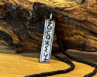 May include: A silver pendant necklace with a rectangular charm featuring a symbol and the word "EMW" on a black beaded chain.