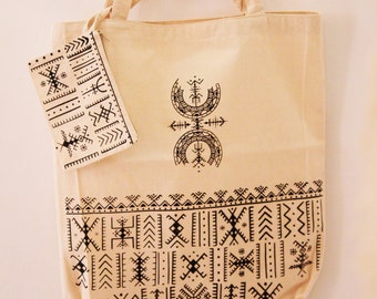 May include: A beige canvas tote bag with black geometric patterns. The bag has a small matching pouch with a zipper closure. The main bag has a large black geometric design in the center and a smaller border of black geometric patterns around the bottom.