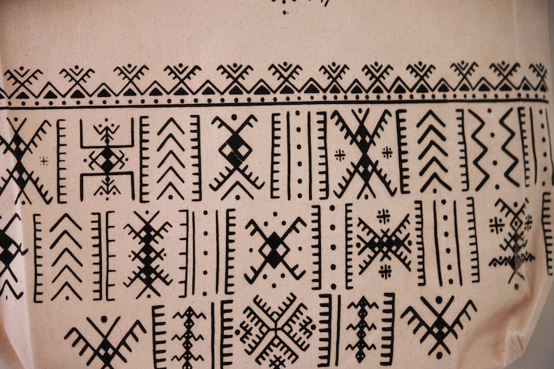 May include: A beige fabric with a black geometric pattern. The pattern is made up of various shapes, including triangles, squares, and zigzags.