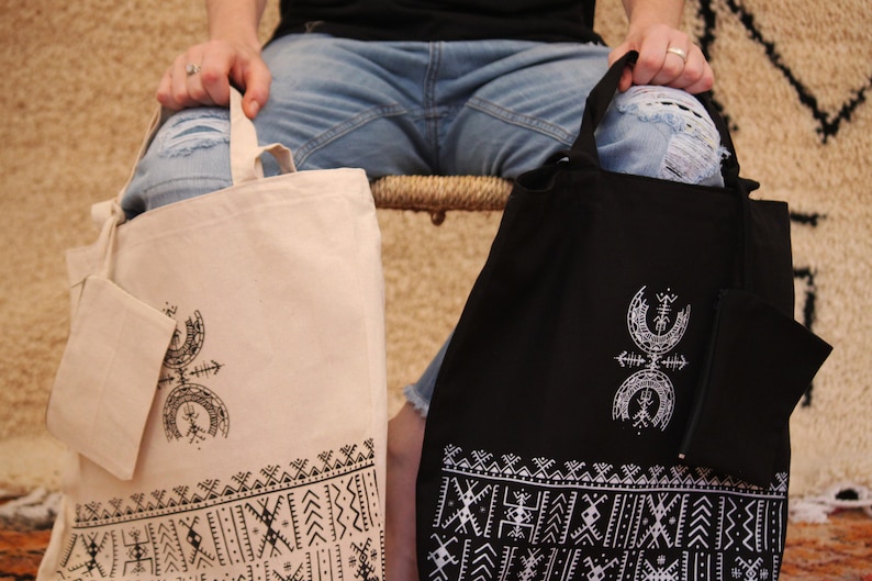 May include: Two tote bags with a geometric design. One bag is beige with black designs and the other is black with white designs.