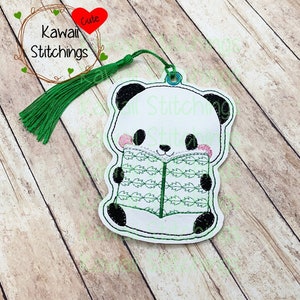 May include: A white panda bear bookmark with black eyes and ears, holding a green book with a leafy pattern. The bookmark has a green tassel attached to the top.