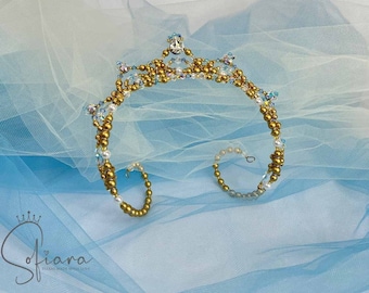 May include: A gold and crystal tiara with a delicate design. The tiara is made with small gold beads and clear crystals. It is a beautiful and elegant piece of jewelry.