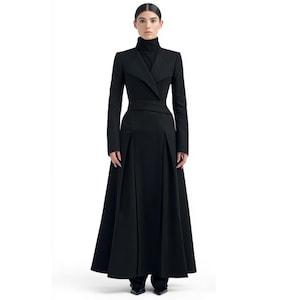 May include: A floor-length black coat featuring a high collar, long sleeves, and a structured bodice with a wide waist belt. The garment has a flared skirt with vertical pleats, creating a full silhouette that extends to the floor in a solid black color.