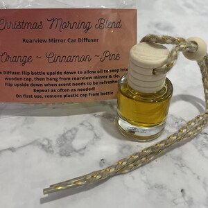 以下が含まれることがあります： 木製のキャップと金色と白の紐が付いた小さなガラス瓶。瓶には透明な液体が入っており、「クリスマスモーニングブレンド リアビューミラーカーディフューザー オレンジ - シナモン - パイン」と書かれたラベルが付いています。拡散するには：瓶を逆さまにして、オイルが木製のキャップに染み込むようにします。その後、リアビューミラーに吊るして紐で結びます。香りが薄くなったら、瓶を逆さまにします。必要に応じて繰り返してください！最初の使用時には、瓶からプラスチック製のキャップを外してください