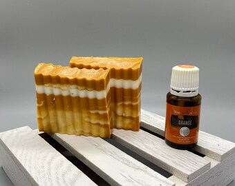 May include: Two bars of orange and white striped soap on a white wooden crate with a small bottle of orange essential oil labeled "You've Got This" and "Orange".