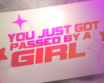 May include: A pink and orange vinyl sticker with the text "You just got passed by a girl" and two pink stars.