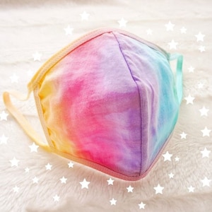 May include: A rainbow tie-dye face mask against a white background. The mask is made from a soft, comfortable fabric and features a tie-dye pattern in shades of pink, purple, blue, and yellow.