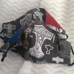 May include: Three face masks with black fabric and white Mjolnir hammer designs. The masks have black elastic straps. One mask has a red fabric lining, one has a blue fabric lining, and one has a gray fabric lining.