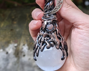 May include: A black and copper wand with a white selenite crystal orb at the end. The wand is decorated with a silver crescent moon charm.
