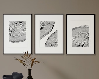 May include: Three black and white framed prints of tree rings. The prints are arranged in a row on a light brown wall. The prints are all different sizes and shapes.