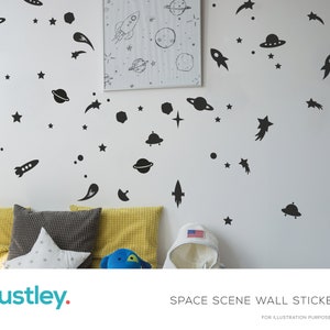 May include: Black and white space-themed wall decals featuring planets, stars, rockets, and a UFO. The decals are on a white wall in a room with a bed and pillows.