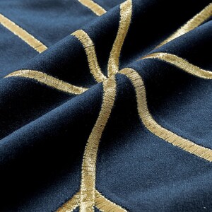 K&ouml;nnte beinhalten: Nahaufnahme eines dunkelblauen Stoffes mit goldener Stickerei in einem geometrischen Muster.