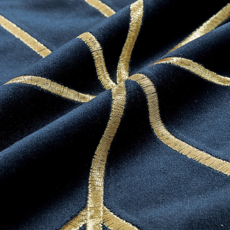 K&ouml;nnte beinhalten: Nahaufnahme eines dunkelblauen Stoffes mit goldener Stickerei in einem geometrischen Muster.
