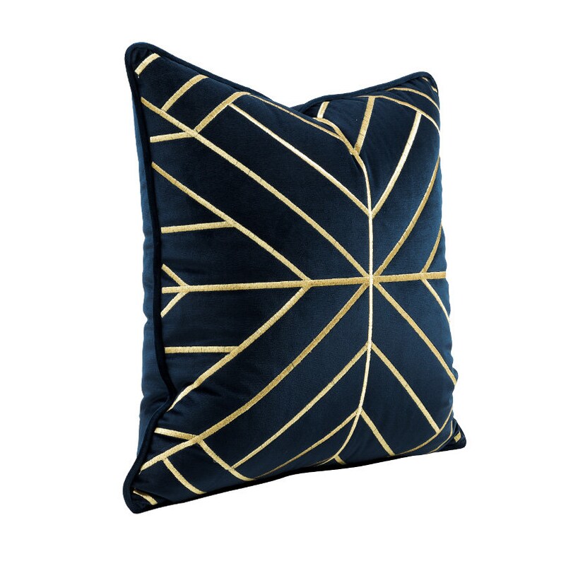 K&ouml;nnte beinhalten: Ein marineblaues Kissen mit einem geometrischen Muster aus goldenen Linien. Das Kissen ist aus Samt und hat eine weiche, luxuri&ouml;se Haptik.