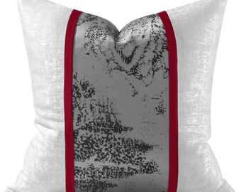May include: White throw pillow with a gray and black abstract design and a red stripe down each side.