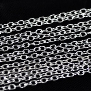 Può includere: Maglie di catena argentate in primo piano. La catena è composta da piccoli anelli ovali.