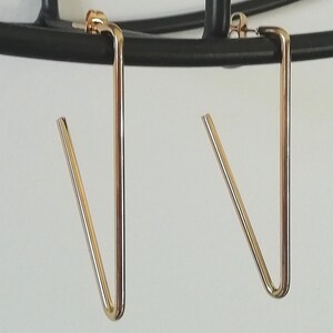 May include: A pair of gold-toned geometric earrings with a V-shaped design.