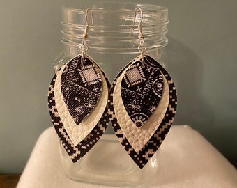 Op de afbeelding: Een paar oorhangers met een gelaagd ontwerp. De oorhangers zijn gemaakt van wit en zwart kunstleer met een paisley-patroon. De oorhangers zijn bevestigd aan zilveren haakjes.