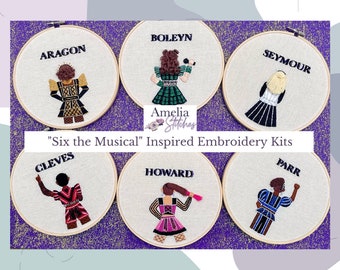 May include: Six embroidery hoop kits featuring the names and portraits of the six wives of Henry VIII: Catherine of Aragon, Anne Boleyn, Jane Seymour, Anne of Cleves, Catherine Howard, and Catherine Parr. The hoops are white with black text and colorful embroidery.