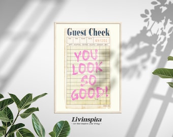 Puede incluir: Una impresión enmarcada con un diseño de cheque de invitado vintage. El texto "You look so good!" está escrito en rosa en el cheque. La impresión está enmarcada en un marco de madera clara y tiene el texto "Livinspira - Art that inspires your living -" en la parte inferior.
