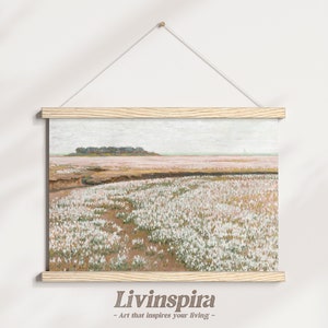 May include: A framed canvas print of a landscape painting featuring a field of white flowers in the foreground, a distant island with trees, and a cloudy sky. The frame is made of light wood.
