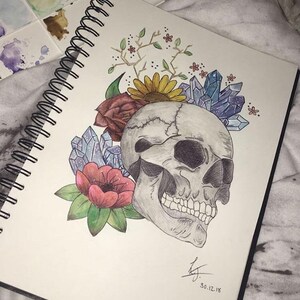 Puede incluir: Una ilustración dibujada a mano de una calavera con flores y cristales. La calavera está dibujada en tonos de gris, mientras que las flores están en tonos de rojo, rosa y amarillo. Los cristales están en tonos de azul y morado.