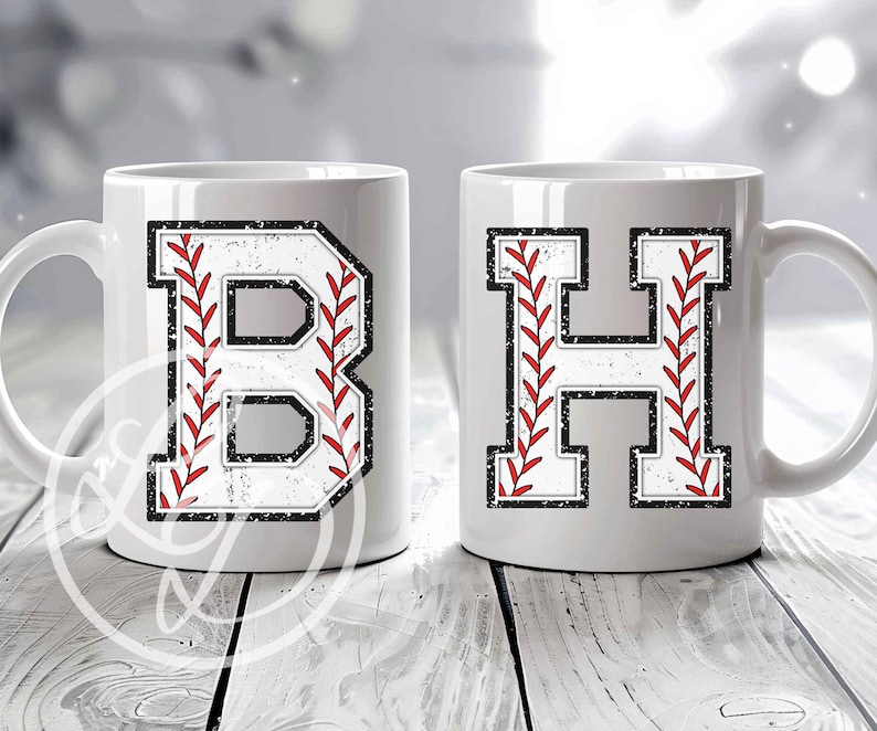 May include: Two white ceramic mugs with baseball-themed letter designs. The mug on the left has a red and white baseball stitch design with the letter "B" in the center. The mug on the right has a red and white baseball stitch design with the letter "H" in the center.