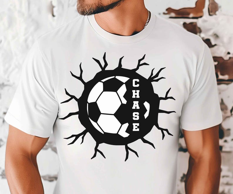 May include: White t-shirt with a black and white soccer ball design. The soccer ball is encircled by a black graphic with the name "CHASE" in white lettering. The design has a cracked, broken effect.