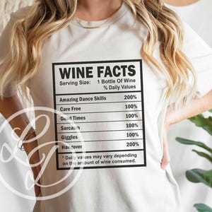 May include: White t-shirt with a black graphic that reads "Wine Facts" and lists the percentage of daily values for things like "Amazing Dance Skills", "Care Free", "Good Times", "Sarcasm", "Giggles", and "Hangover".