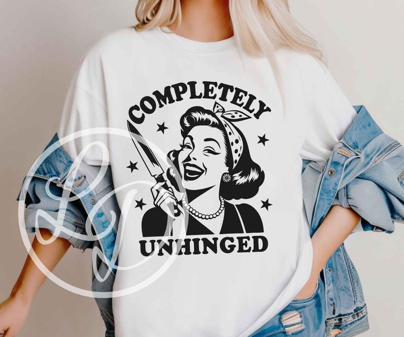 May include: White t-shirt featuring a black and white graphic of a vintage woman holding a knife, with the words "COMPLETELY UNHINGED" in a circular design. The design includes stars and a retro aesthetic.