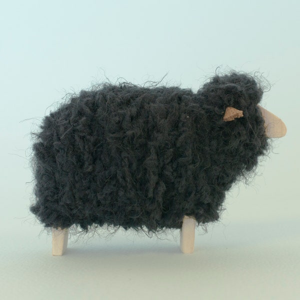 Minimalistische schwarze Schaf Figur, aus Holz und flauschigem Fleece. Flaches Gesicht.