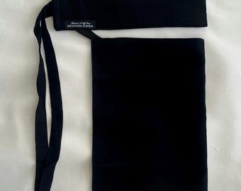 May include: A solid black niqab featuring a rectangular headband and a long, rectangular face veil. A small black fabric label is attached to the headband, displaying the white text "BEDOON ESSM" along with Arabic script above the brand name.