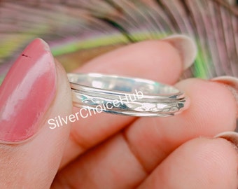 May include: A silver ring with a hammered texture. The ring is made of three bands that are stacked on top of each other. The ring is shown on a finger.