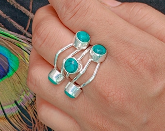 May include: A silver ring featuring three round, bezel-set turquoise stones. The band consists of three separate, thin, polished silver wires that curve and connect to hold each individual stone in a vertical arrangement across the finger.