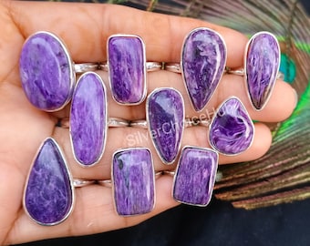 May include: A collection of ten silver rings with purple gemstone settings. The rings feature a variety of shapes, including oval, teardrop, and rectangular.
