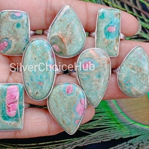 May include: Nine silver rings with green and pink gemstone settings. The gemstones are a mix of oval, teardrop, and rectangular shapes.