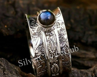 May include: A silver ring with an intricate design and a blue labradorite gemstone. The ring is made of sterling silver and has a spinning band.