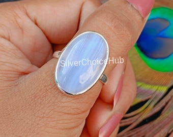 May include: A silver ring featuring a large, oval-shaped, light blue chalcedony gemstone with subtle white banding. The smooth, polished stone is set in a simple silver bezel. The text SilverChoiceHub is visible across the center of the stone.