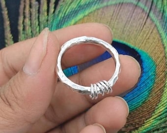 May include: A silver ring featuring a hammered, textured band with a section of the ring wrapped in multiple coils of thin silver wire. The metal has a bright, reflective finish, and the design incorporates a series of small, uniform loops.