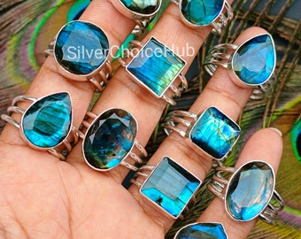 May include: Ten silver rings with iridescent blue labradorite gemstones. The rings feature a variety of shapes, including oval, square, and teardrop.