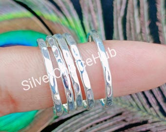 May include: Five silver hammered stacking rings. The rings are all the same width and have a textured surface.