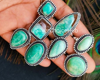 May include: Set of seven silver rings with green gemstone settings. The rings feature various shapes and sizes of gemstones, including oval, teardrop, and square.