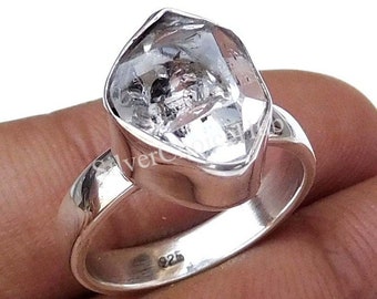 May include: A silver ring with a large, clear, faceted gemstone. The ring is marked "925" on the band.