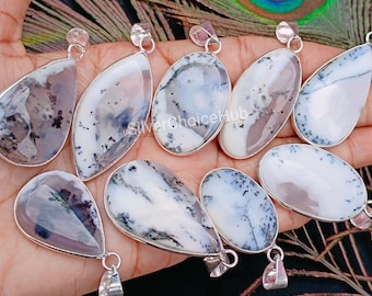May include: A collection of eight silver dendritic agate pendants. The pendants are teardrop shaped and have a white background with black dendritic patterns. The pendants are all different sizes and shapes.