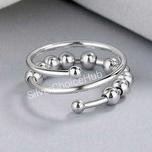 Può includere: Un anello d'argento con un design a doppia fascia. La fascia è decorata con una serie di piccole perle rotonde.