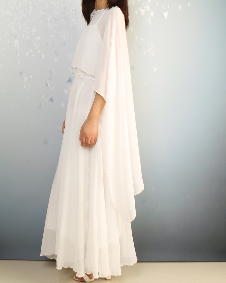 K&ouml;nnte beinhalten: Ein wei&szlig;es Maxikleid mit einem flie&szlig;enden Umhang. Das Kleid hat ein schlichtes, elegantes Design und ist perfekt f&uuml;r einen besonderen Anlass.