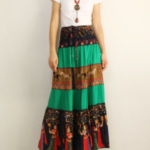 May include: A long, flowing maxi skirt with a multi-colored, patterned design. The skirt features a green, brown, and black color scheme with a variety of floral and geometric patterns. The skirt has a drawstring waist and a tiered design.